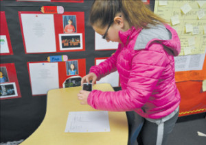 Bullis Charter School fifth-grader Anna Morokutti takes a photo of a document to upload to her FreshGrade account. 